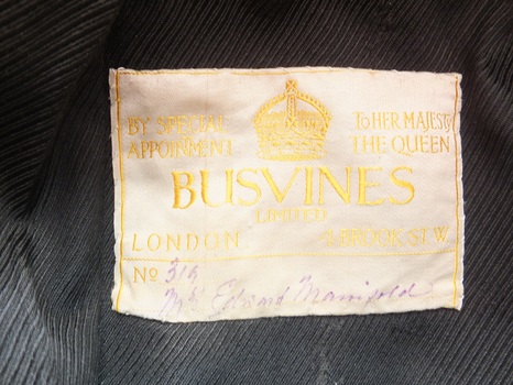 Light coloured label with embroidered gold thread and handwritten details