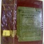 Crimson hardcover book with green sticker on the front cover, all covered in clear plastic