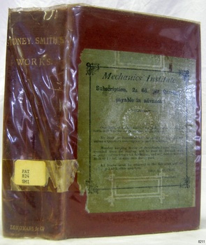 Crimson hardcover book with green sticker on the front cover, all covered in clear plastic
