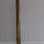 side profile of a shiny brass telescope, upright on its lens end. The surface has some dents.
