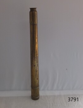 side profile of a shiny brass telescope, upright on its lens end. The surface has some dents.