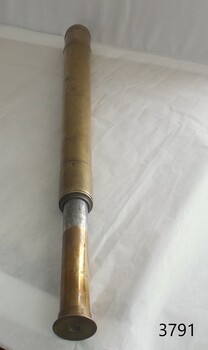 Telescope laying on bench with eyepiece closest to the viewer. 