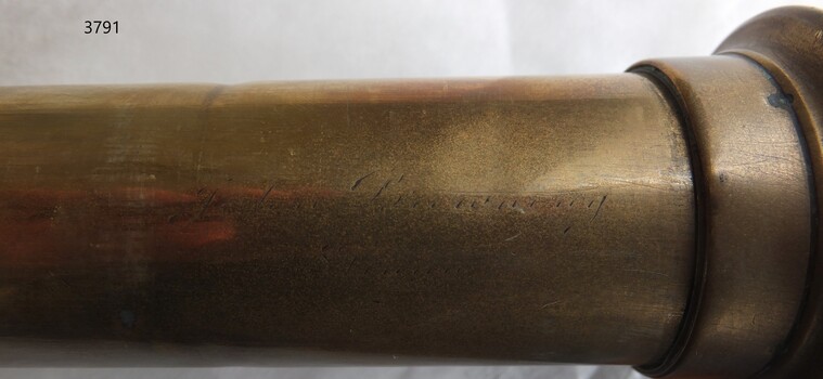Engraved inscription in cursive script on the side of the telescope