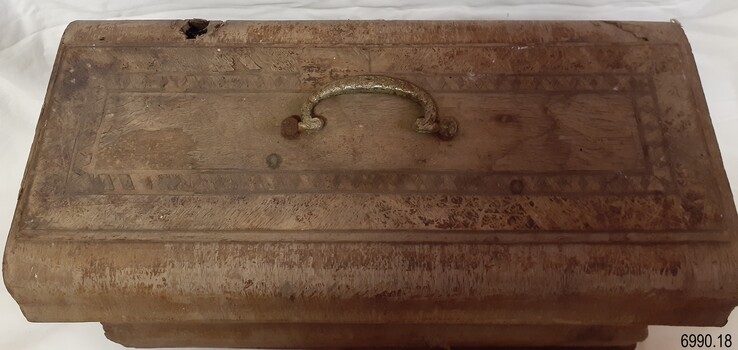 Case top has inlaid wood border. Metal handle has engraved pattern. Hole is in one side.