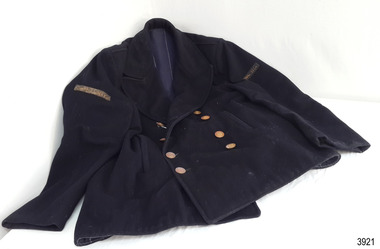 Front of navy blue jacket, double breasted, eight buttons on front, labels on sleeves, blue lining with white stripes. Buttons have emblem.