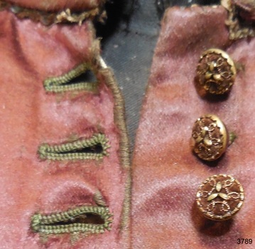 Decorative round buttons of burgundy and gold, and buttonholes shaped to fit the round buttons