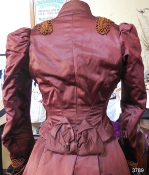 Jacket is fitted close to body and finished at the waist with a ribbon