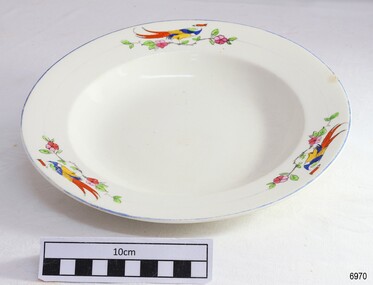 White plate with blue rim and decorated with motifs of a bird of paradise above floral branch