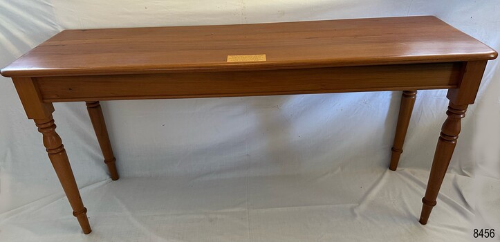 Timber table in location showing brass plaque on top