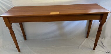 Timber table in location showing brass plaque on top