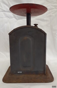 Case of scale is grey metal on a metal foot with sides curved outwards.