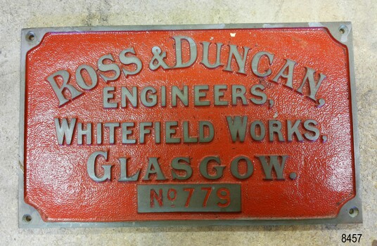   Brass nameplate, red painted background, brass embossed text