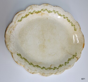 White oval plate with scalloped edges and green leaf border.