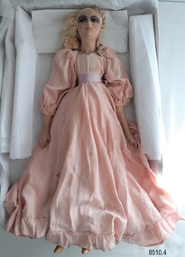 Front view of a cloth and porcelain doll wearing a long pink dress.
