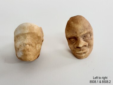 Two white clay tobacco pipe heads, each with a join line from forehead to chin
