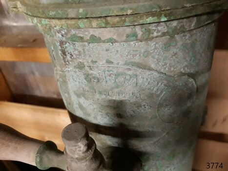 Close-up view of the maker's plate, partly obscured by the plumbing fitting