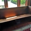 The pew is along the west wall facing inward to the club room and backrest next to window