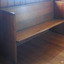 The pew is inside the doorway facing into the school room. It is along the east wall against the south wall.