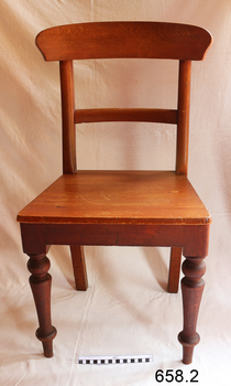 The wooden chair is facing the camera. It has turned legs.