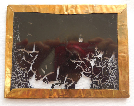 The gilt frame's edges is roughly folded over the edge of the glass