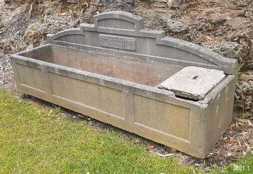 On the right end of the trough there is a small division that has a removable concrete cap that covers the opening. There is a depression in the centre of the cap that possibly once had a handle fitted there. This end of the trough has several chipped areas of damage. Inside the larger side of the trough there are colour changes in the concrete that are likely to have been caused by different levels and types of contents.