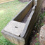 The base of the pediment is wider than its top and rests solidly on the trough’s base. There is some chipping on the top back of the pediment that shows the metal reinforcing inside it. 