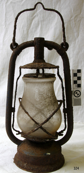 A large lamp with a carrying handle. Metal is rusted.