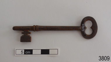 Iron latch key on bench. Oval handle.
