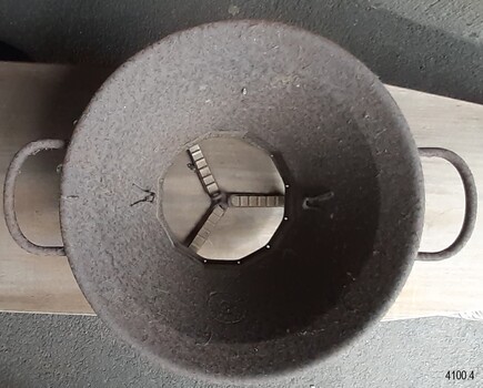 Metal chamber has inscription, clips for holding discs in place and three braces below the food exit