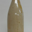 A beige stoneware bottle, possibly originally containing ginger beer. No stopper.
