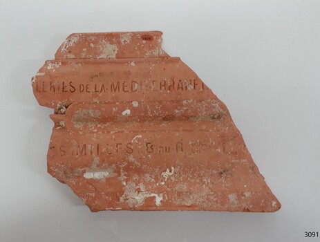 Orange roofing tile with inscriptions and encrustations on its surface
