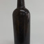 Tall slim dark coloured bottle with narrow neck. Glass is shiny. Remnants of tape and wire around the neck.