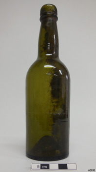 Light shines green through glass. Sediment and pontil mark are visible through glass