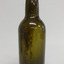 Light shines through green glass. Sediment down one side. Pontil mark is visible.