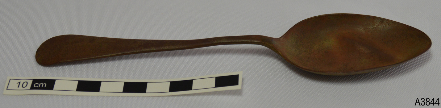 Tablespoon has bowl facing upwards. Metal is a brown colour.