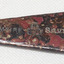 Metal is part shiny with red, brown, beige and black discolouration's. Embossing is in silver.