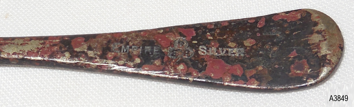 Metal is part shiny with red, brown, beige and black discolouration's. Embossing is in silver.