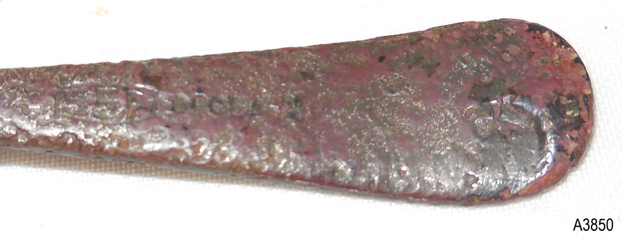 Logo and embossed marks are worn but visible. Discolouration of brown, red, light and dark. Handle has rounded tip.
