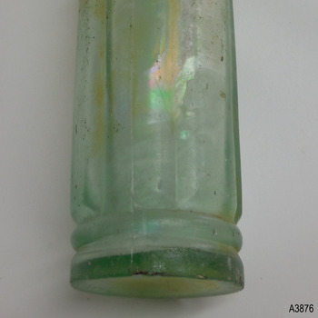 Bottle has side seam, heel has uneven thickness, glass has bubbles and imperfections.