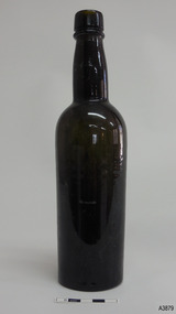 Round bottle has shiny dark glass, is tall and slim and tapers towards base.