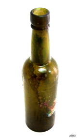 Bottle is tall and slim, olive green in colour, with remnants of label on the base