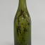 Shiny green glass bottle standing upright. Bottle has blob top. Sediment is inside the bottle.