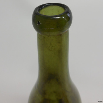 Blob top on bottle has bumps of glass like pimples. Concentric horizontal lines around neck in glass.