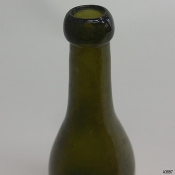 Bottle's lip has a glass 'pimple'. Glass has horizontal concentric lines.