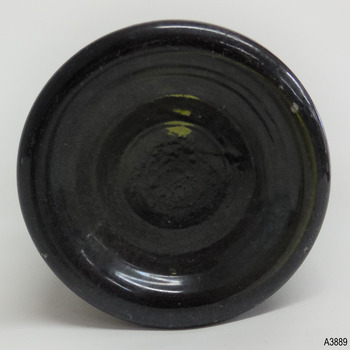 Base has imperfections in glass, is pushed up into bottle and has several rings formed within the glass.