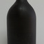 Bottle is black glass, has broken mouth, short neck, broad shoulder, body tapering slightly inwards