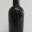 Black bottle has broken mouth, applied ring lip, bulbous neck, creases, lines, scratches and chips in the surface.
