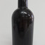Black bottle has broken mouth, applied ring lip, bulbous neck, creases, lines, scratches and chips in the surface.