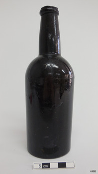 Black bottle has broken mouth, applied ring lip, bulbous neck, creases, lines, scratches and chips in the surface.