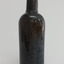Black glass bottle is tall and slim, has an applied lip and slightly bulbous neck. There is a seam at the choulder.